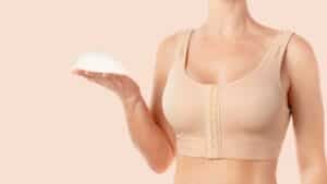 Woman wearing compression bra and holding an implant in her hand