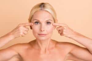 Woman pointing to eyelid area to indicate cosmetic surgery