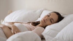 Woman asleep in bed laying on back after breast augmentation
