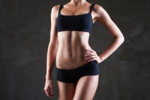 Woman showing a toned abdominal contour after body contouring surgery.