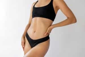 Woman showing natural body contours after mommy makeover.